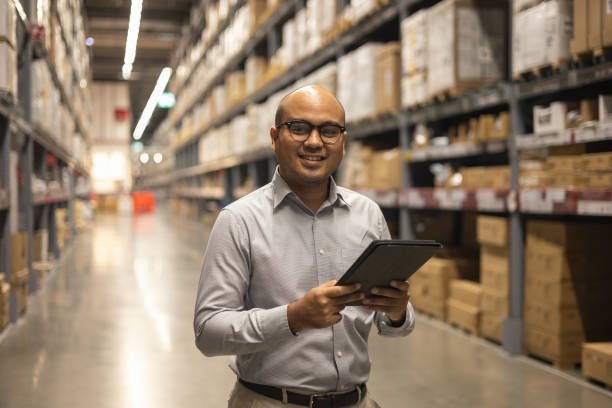 Young manager worker checklist manage parcel box product in warehouse. Asian supervisor man using tablet working at store industry. Logistic import export concept. stock photo