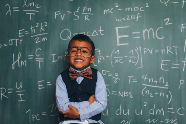 Young Math Nerd Boy in Classroom A young nerd boy dressed in sweater, eyeglasses sits in front of a chalkboard full of math equations in a school classroom. He has an inquisitive smile on hisr face and is ready to excel in academics. e=mc2 stock pictures, royalty-free photos & images