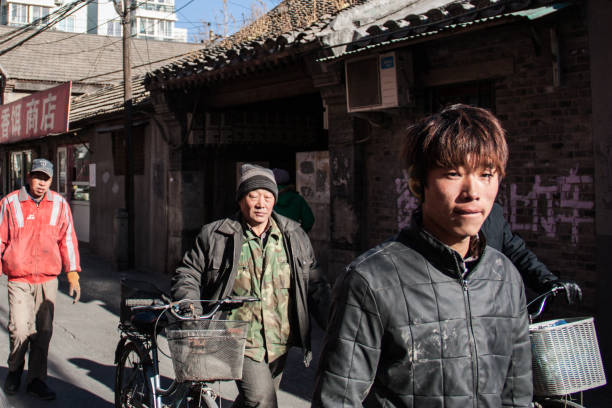 Young migrant workers walk in an Hutong alley in the cold winter in Beijing, China stock photo