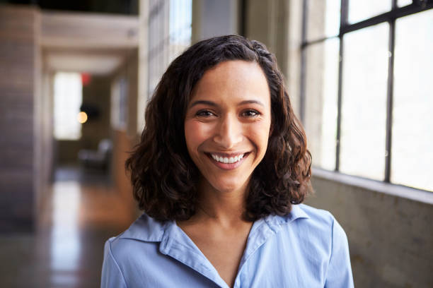 Young mixed race businesswoman smiling to camera Young mixed race businesswoman smiling to camera button down shirt photos stock pictures, royalty-free photos & images