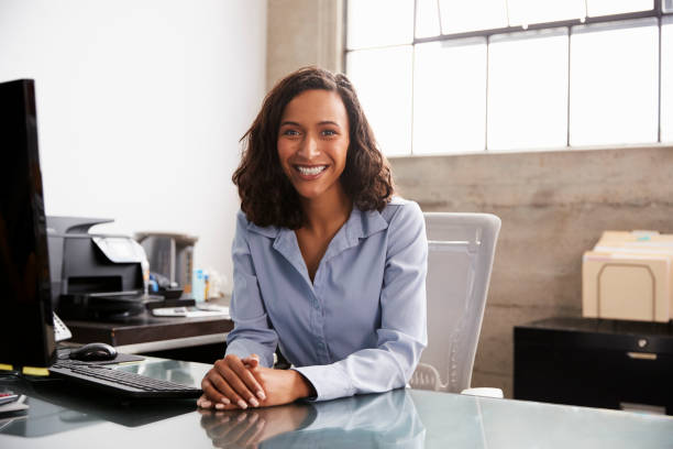 Young mixed race woman at office desk smiling to camera Young mixed race woman at office desk smiling to camera mental health professional photos stock pictures, royalty-free photos & images