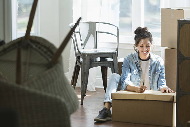 young mixed race woman moving, writing checklist - alleen één jonge vrouw stockfoto's en -beelden