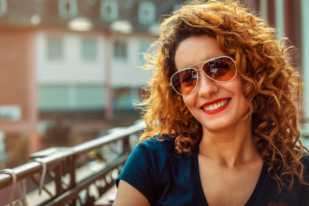 young moroccan woman, with curly brown hair, sitting in an outdoor cafe in Mainz, wearing sunglasses stock photo
