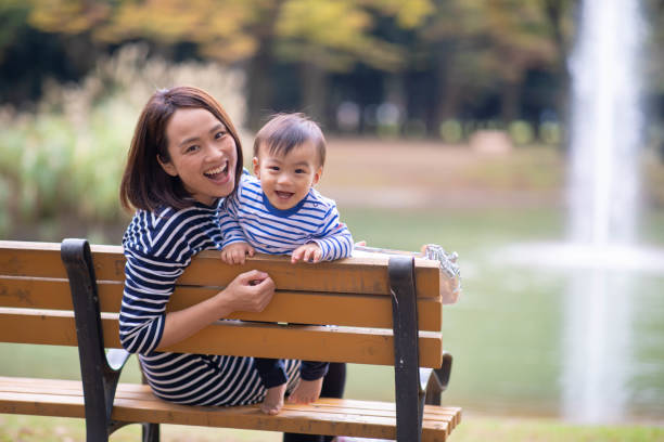 jonge moeder en zoon kijken camera in openbaar park - alleen japans stockfoto's en -beelden