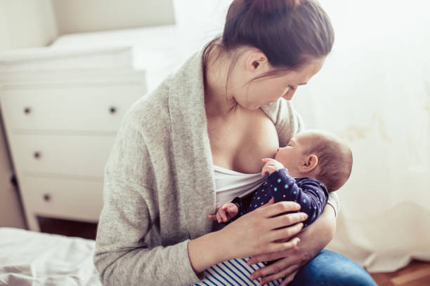 Young mother breastfed her baby girl. Mother breastfed baby at the bedroom. stock photo