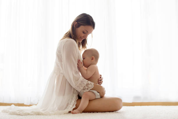 Young mother breastfeeding her newborn baby boy at home stock photo