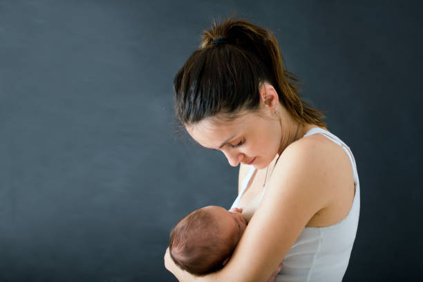 Young mother, breastfeeding her newborn baby boy stock photo