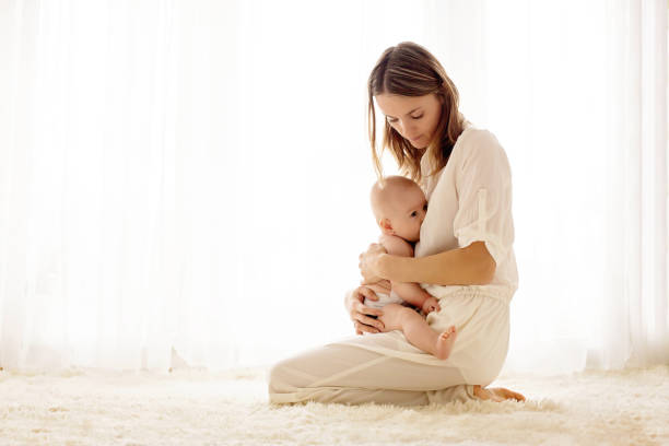 Young mother breastfeeding her newborn baby boy stock photo