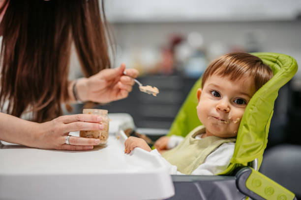 Young Mother Feeding A One Year Old Boy stock photo