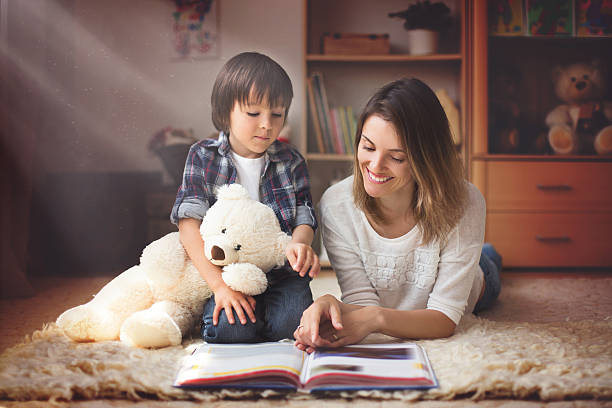 молодая мать, чтение книги, чтобы ее ребенок, мальчик - teddy ray стоковые фото и изображения