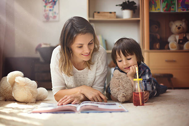 joven madre, leer un libro un su hijo, niño - teddy ray fotografías e imágenes de stock