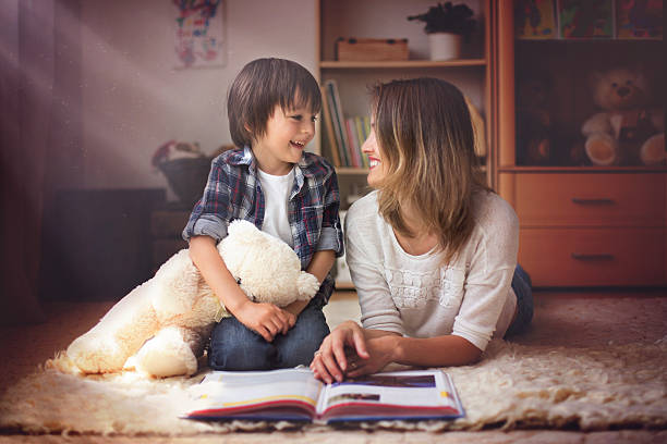 młoda matka, poczytać książkę do jej dziecko, chłopiec - teddy ray zdjęcia i obrazy z banku zdjęć