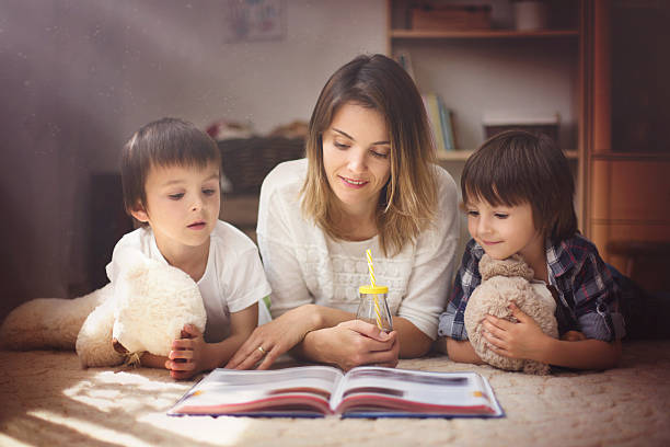 молодая мать, читать книги для своих двух детей, мальчиков - teddy ray стоковые фото и изображения