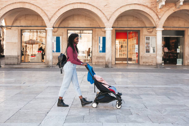 Young mother walking with her baby girl in city downtown stock photo