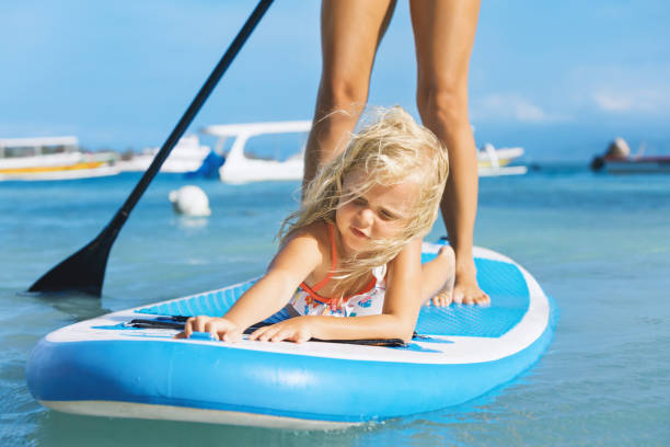 Young mother with little clild paddling on stand up paddleboard stock photo