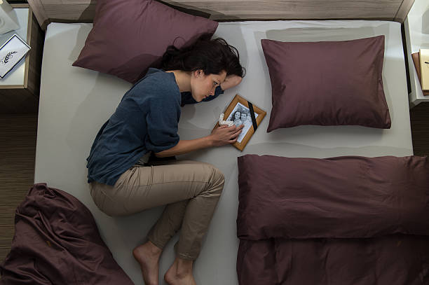 Young mourning woman lying in bed stock photo