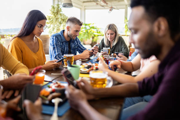 jóvenes amigos multiculturales que usan el teléfono móvil - concepto de teléfono inteligente adicción - social networks food places fotografías e imágenes de stock