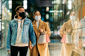 冬の病気予防のための保護フェイスマスクを着用しながら、街で若い多民族カップルの買い物