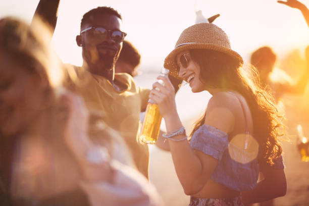 Young multi-ethnic hipster friends dancing at summer beach party Happy multi-ethnic hipster friends drinking, dancing, partying and having fun at the beach at sunset drink beer stock pictures, royalty-free photos & images