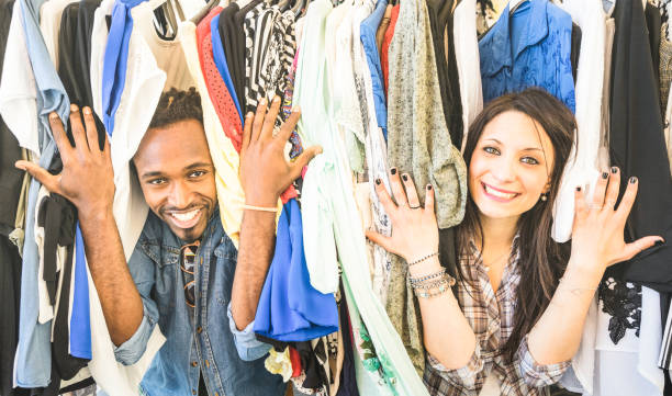 Young multiracial couple having fun at clothing flea market - Best friends sharing time shopping on cheap sale - Lovers enjoying everyday life moments - Wardrobe fashion shop concept with happy people Young multiracial couple having fun at clothing flea market - Best friends sharing time shopping on cheap sale - Lovers enjoying everyday life moments - Wardrobe fashion shop concept with happy people thrift store stock pictures, royalty-free photos & images