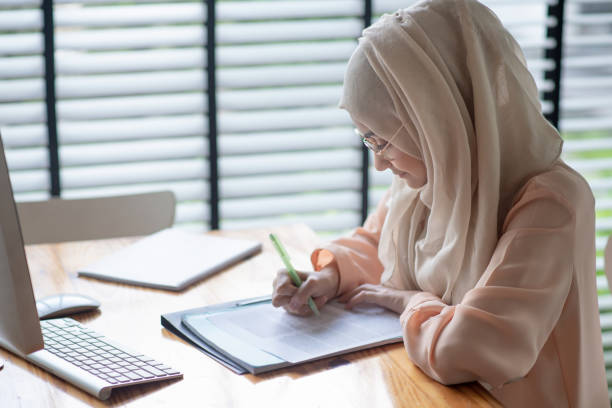 jonge islamitische student schrijven en het werken in traditionele kleding. - arabic student stockfoto's en -beelden