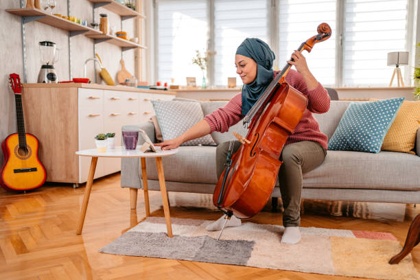 Young Muslim Woman Watching A Tutorial On Tablet On How To Play Cello stock photo