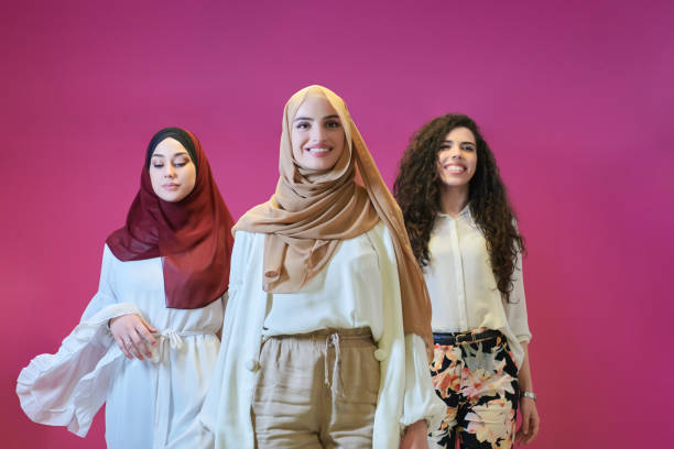 Young muslim women posing on pink background stock photo