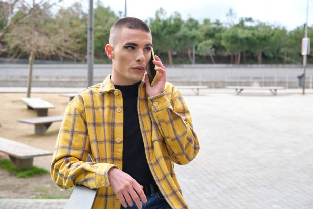 Young non binary person talking by his smartphone. Make up androgynous person. stock photo