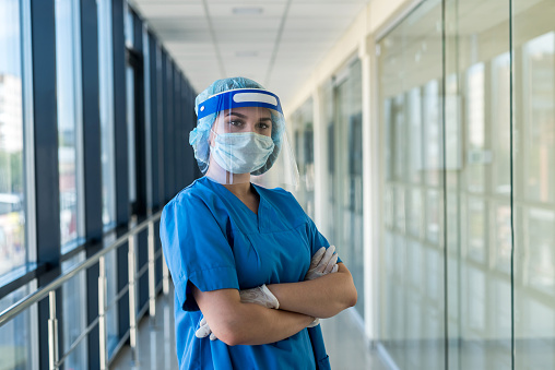 portrait of a young nurse in a blue uniform and a protective shield to protect against a new dangerous virus covid19
