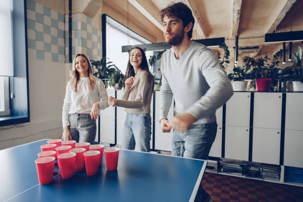 Young people coworkers playing beer pong in modern office stock photo