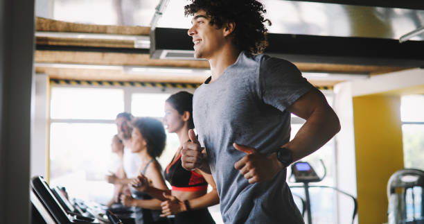 Young people running on a treadmill in health club. stock photo