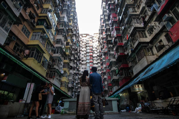 Young people visit a living quarters of densed buildings in Kowloon, Hong Kong, and take photos and selfies. stock photo