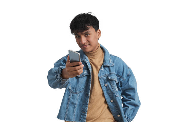 Young peruvian man smiling and giving the smartphone to the camera, isolated. stock photo