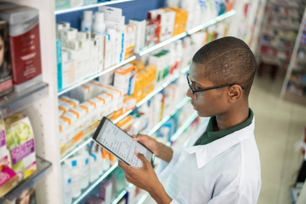 Young pharmacist checking the shelves with a digital tablet at the pharmacy Young pharmacist checking the shelves with a digital tablet at the pharmacy generic drug stock pictures, royalty-free photos & images