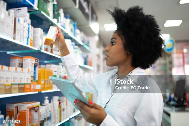 Young pharmacist checking the shelves with a digital tablet at the pharmacy