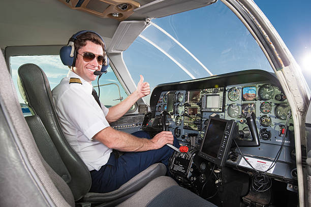 Young pilot in aircraft cockpit giving thumbs up stock photo