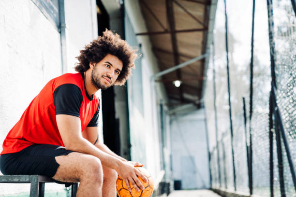 Young player sitting outside soccer court stock photo