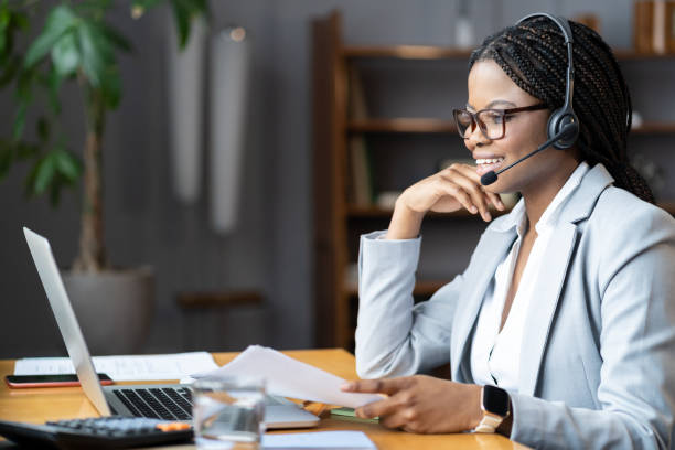 Young positive afro female using wireless headset for remote work during maternity leave stock photo