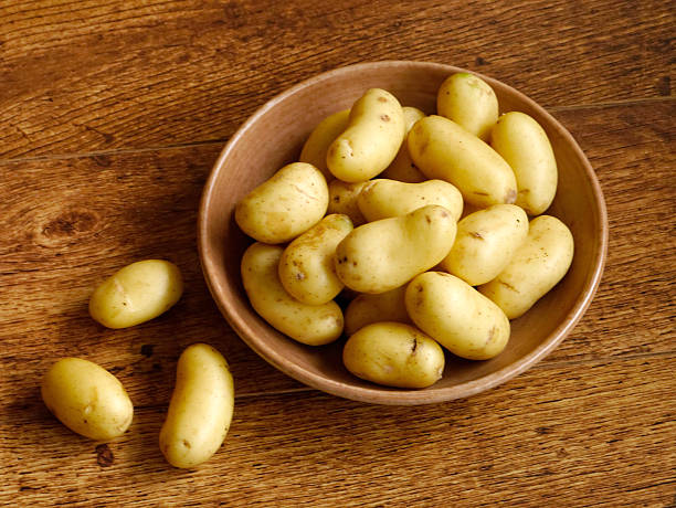 Young potatoes in bowl on wooden table stock photo