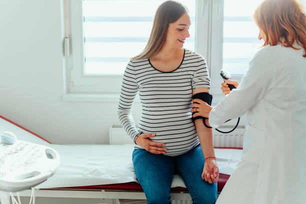 Young pregnant woman checking blood pressure at medical office stock photo