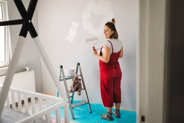 jonge zwangere vrouw die kinderkamer schildert - kinderkamer stockfoto's en -beelden