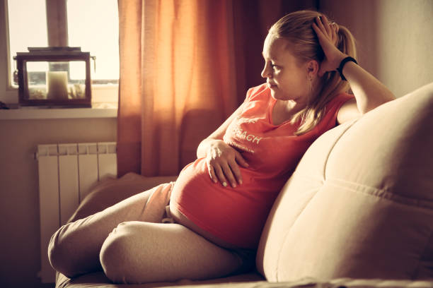 Young pregnant woman relaxing at home stroking her belly. stock photo