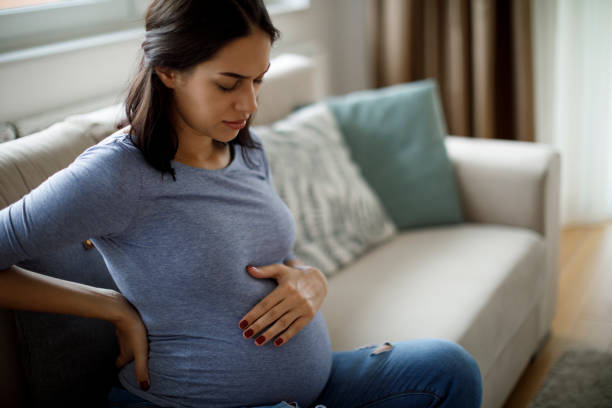 junge schwangere leidet unter rückenschmerzen - schmerz fotos stock-fotos und bilder