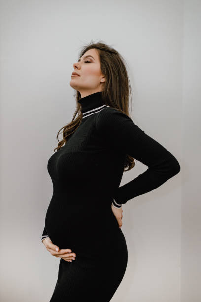 Young pregnant woman wearing a black dress at home stock photo