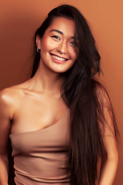 young pretty asian woman cheerful smiling posing on warm brown background, lifestyle people concept young pretty asian woman cheerful smiling posing on warm brown background, lifestyle people concept closeup hot middle eastern women stock pictures, royalty-free photos & images