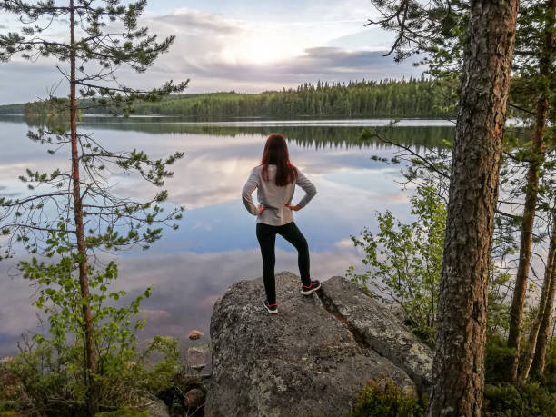 Young pretty woman standing on stone on lake shore and looking on sunset in north Sweden Young pretty woman standing on big stone on lake shore and looking on sunset in north Sweden beautiful swedish women stock pictures, royalty-free photos & images