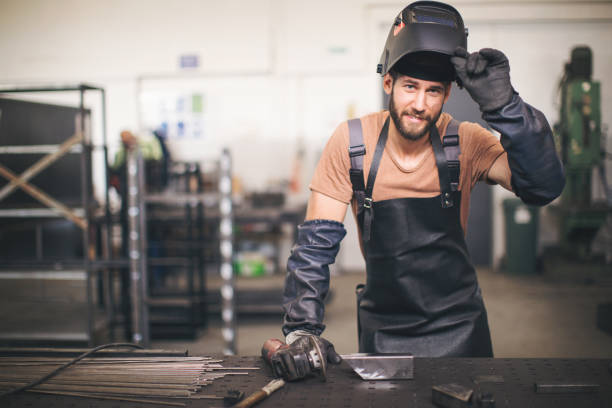 Young professional welder grinding and welding metal bars stock photo