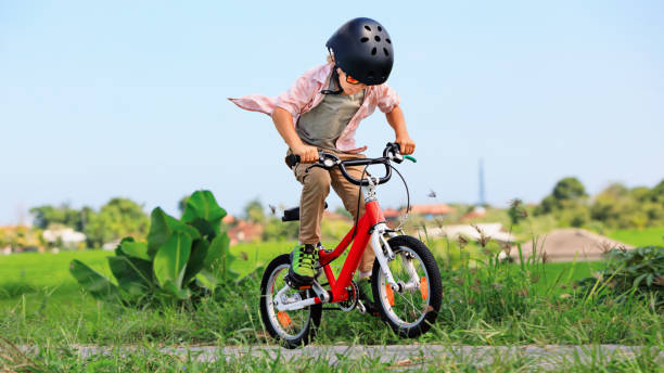 Young rider kid in helmet and sunglasses riding bicycle stock photo
