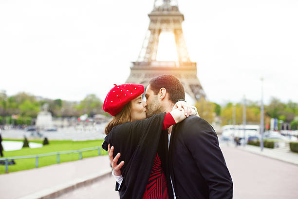 Young romantic couple kissing near the Eiffel Tower in Paris stock photo