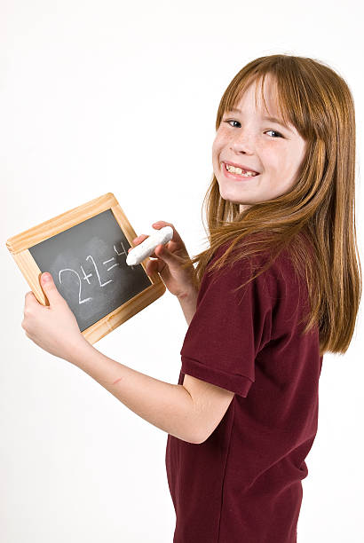 Young school girl writing on chalk board stock photo